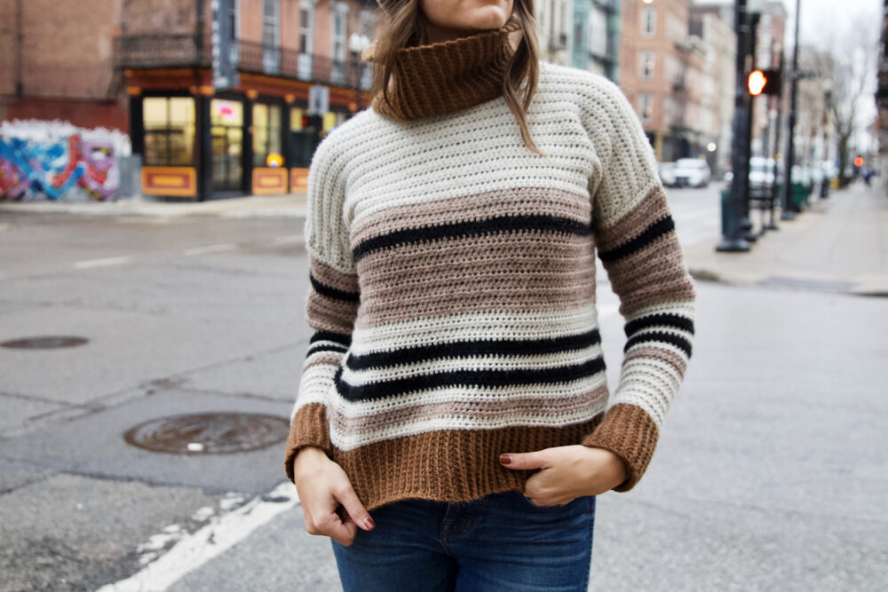 a woman wearing a striped turtleneck crochet sweater