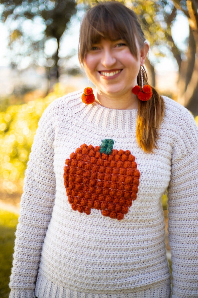 a woman wearing a pumpkin crochet sweater
