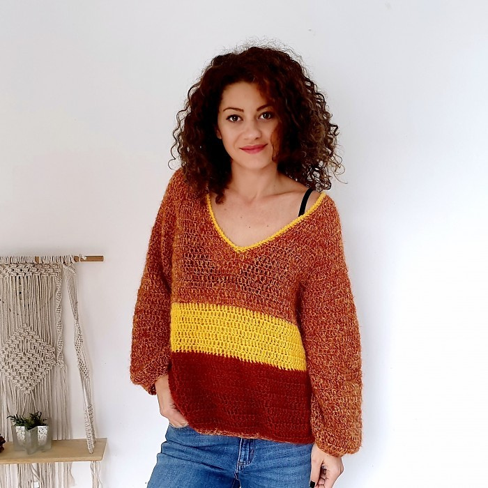 a woman wearing a crochet sweater in rusty gold color