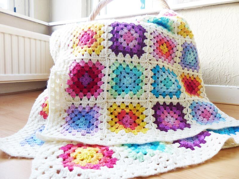 colorful rainbow granny square crochet blanket on a basket on the floor