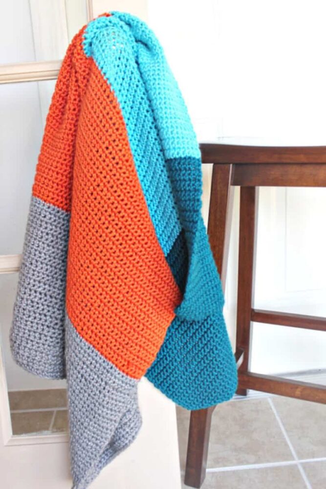 color block crochet blanket hanging on a door knob